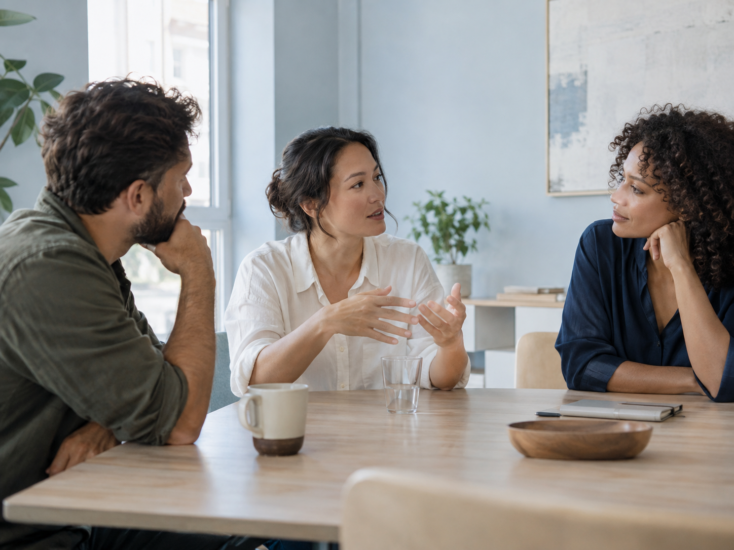 Three colleagues listening to each other around a table