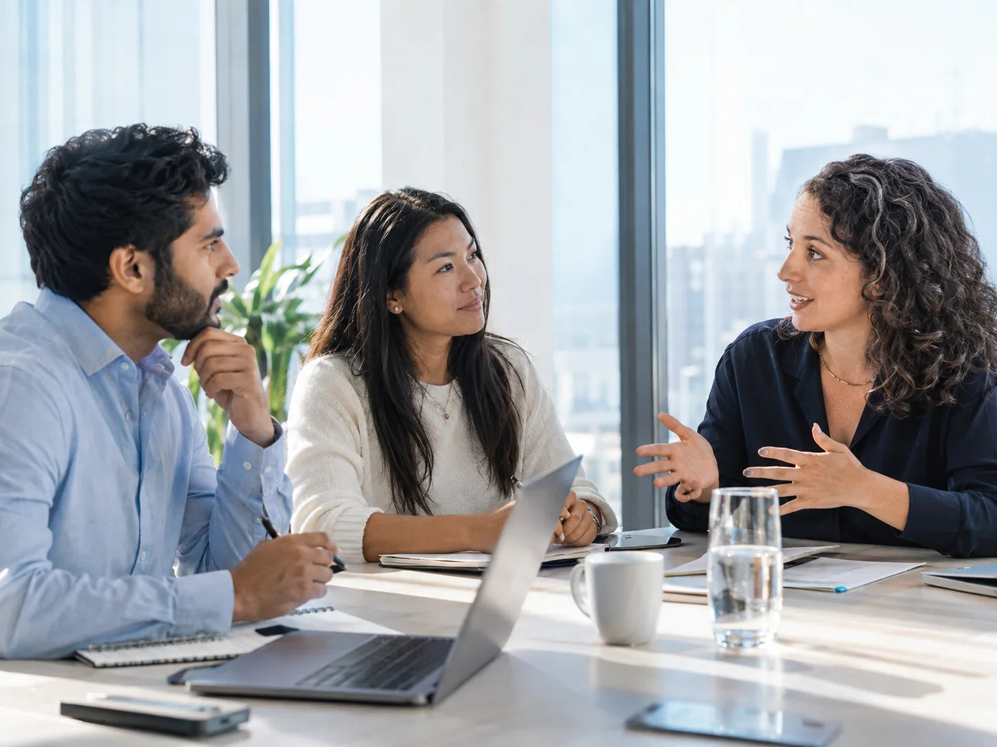 Three colleagues listening to each other around a table